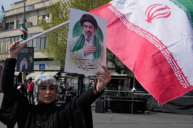 A woman displays a poster of the Iranian Supreme Leader Ayatollah Mojtaba Khamenei in downtown Tehran, 14 March, 2026