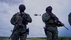 Ekvador Milagro'da iki askeri personel, bir helikopterin önünde.