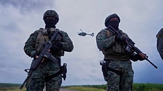Ekvador Milagro'da iki askeri personel, bir helikopterin önünde.