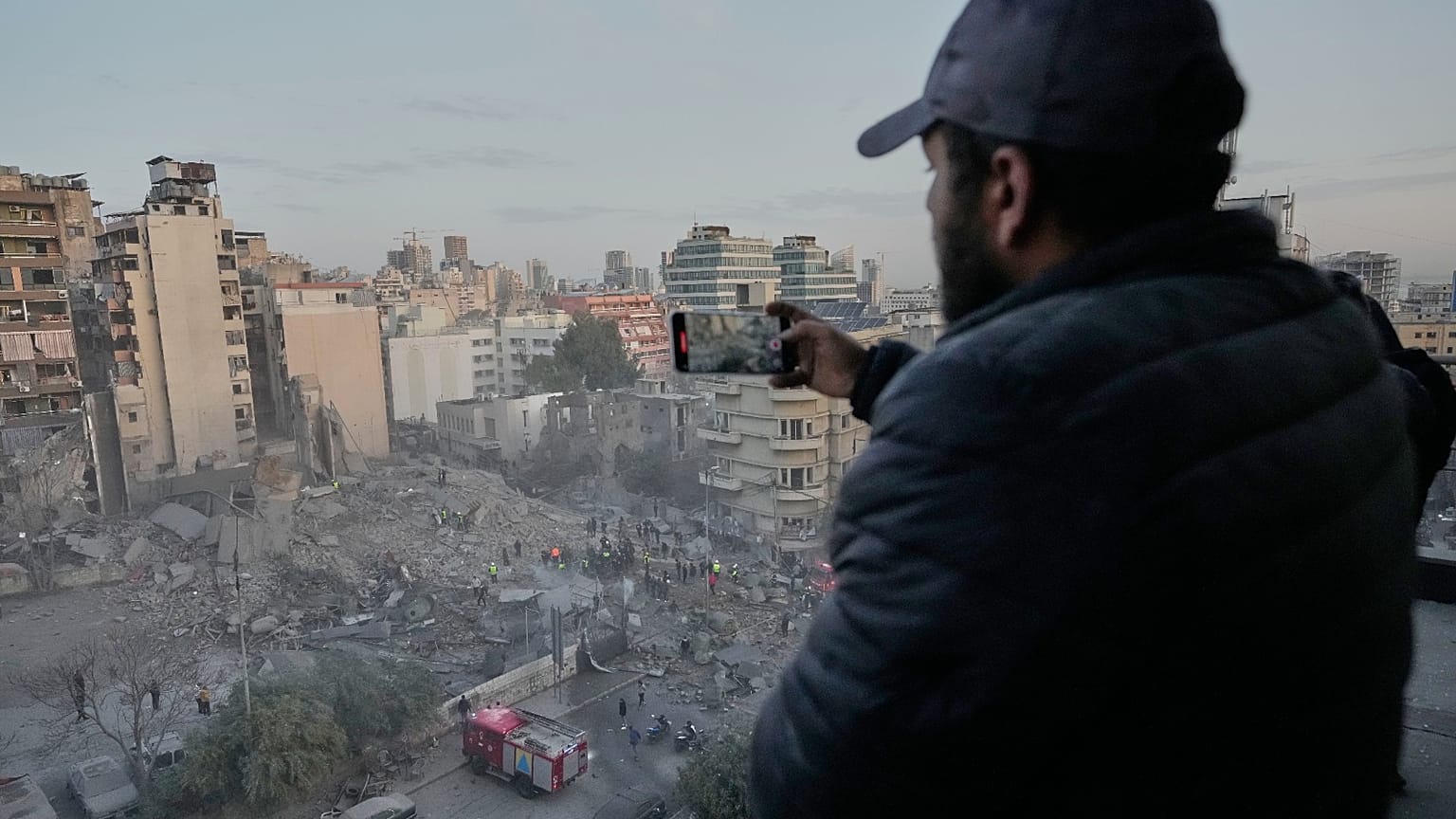 رجل يسجل المشهد على هاتفه بينما يبحث عمال الإنقاذ بين أنقاض مبنى دمر في غارة جوية إسرائيلية في وسط بيروت، لبنان، الأربعاء 18 مارس 2026.