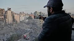رجل يسجل المشهد على هاتفه بينما يبحث عمال الإنقاذ بين أنقاض مبنى دمر في غارة جوية إسرائيلية في وسط بيروت، لبنان، الأربعاء 18 مارس 2026.