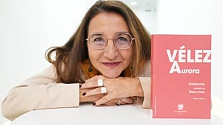 Aurora Vélez resting her chin on her hands posing with her book.