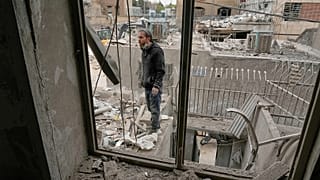 A man stands on the wall of a residential building damaged when a nearby police station was hit in Tehran, 15 March, 2026