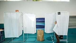 Des électeurs se tiennent dans les isoloirs lors du premier tour des élections municipales à Paris, le dimanche 15 mars 2026.