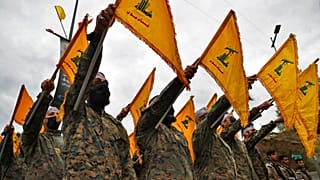 مقاتلون من حزب الله يرفعون العلم خلال مراسم إحياء الذكرى الثانية للقائد الإيراني قاسم سليماني، في الضاحية الجنوبية لبيروت، في 4 يناير 2022.