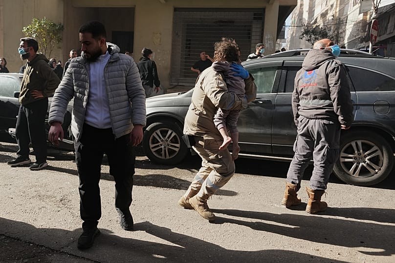 A rescue worker carries a child at the scene of an Israeli airstrike in central Beirut, Lebanon, Wednesday, March 18, 2026