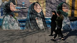 نساء يَمْشِينَ بجانب جدارية على جدار مدرسة للبنات في وسط طهران بإيران، يوم الأربعاء 25 فبراير 2026