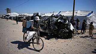 رجل يدفع دراجته الهوائية أمام سيارة صدمتها غارة إسرائيلية أسفرت عن مقتل شخصين في خان يونس جنوب قطاع غزة.