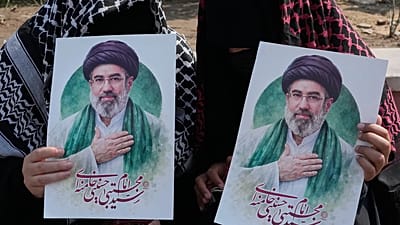 Women hold posters of the Iranian Supreme Leader Ayatollah Mojtaba Khamenei in downtown Tehran, 14 March, 2026