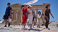 تجول السياح بالمظلة أمام معبد البارثينون القديم في تلة الأكروبوليس، الخميس 26 يونيو 2025، مع وصول أول موجة حر صيفية إلى اليونان، حيث من المتوقع أن تتجاوز درجات الحرارة 40 درجة