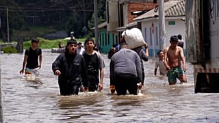 People walk in deep flood water