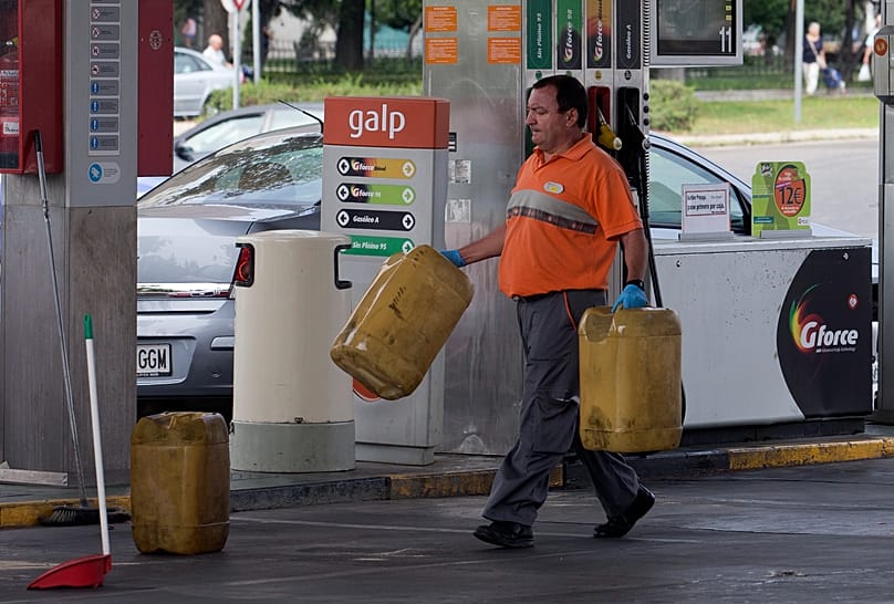 A worker carries plastic containers to be filled with gas at a gas station in Madrid, 28 August, 2013