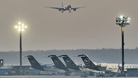 A plane comes in for landing as Lufthansa aircraft are parked at the airport in Frankfurt, Germany, Thursday, March 12, 2026.