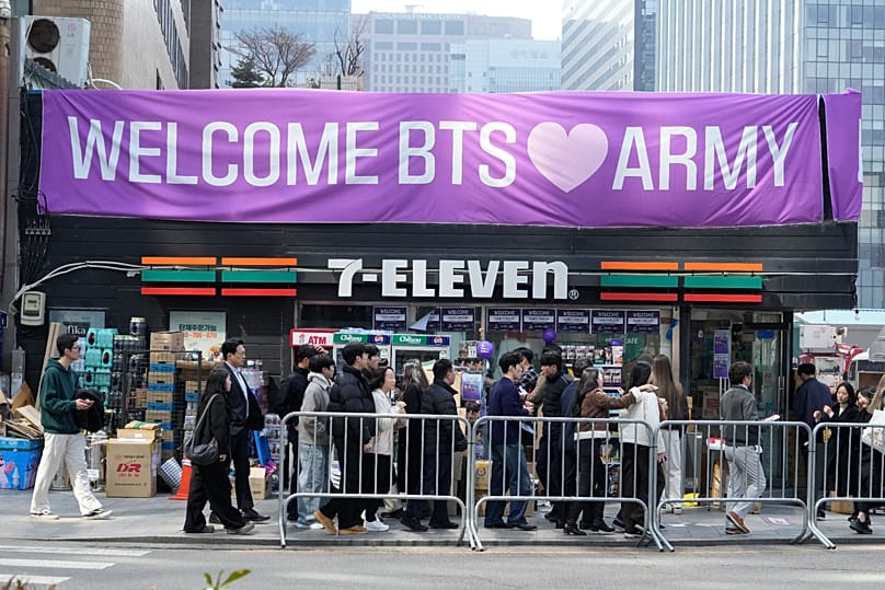 People pass by a banner for BTS ahead of a comeback concert of the K-pop band near Gwanghwamun Square in Seoul, South Korea