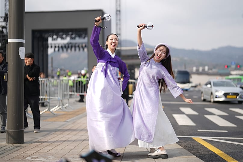 Fans of K-pop band BTS, South Korean Chaemin Shin, left, and Vietnamese Tam Tamie, right, and sing at Gwanghwamun Square in Seoul, South Korea.
