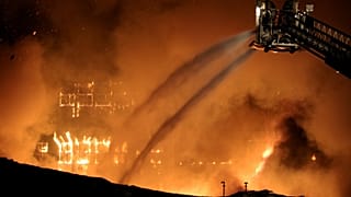  يعمل رجال الإطفاء من شاحنة منصة بينما تدمر النيران مجمع مصنع بوش السابق