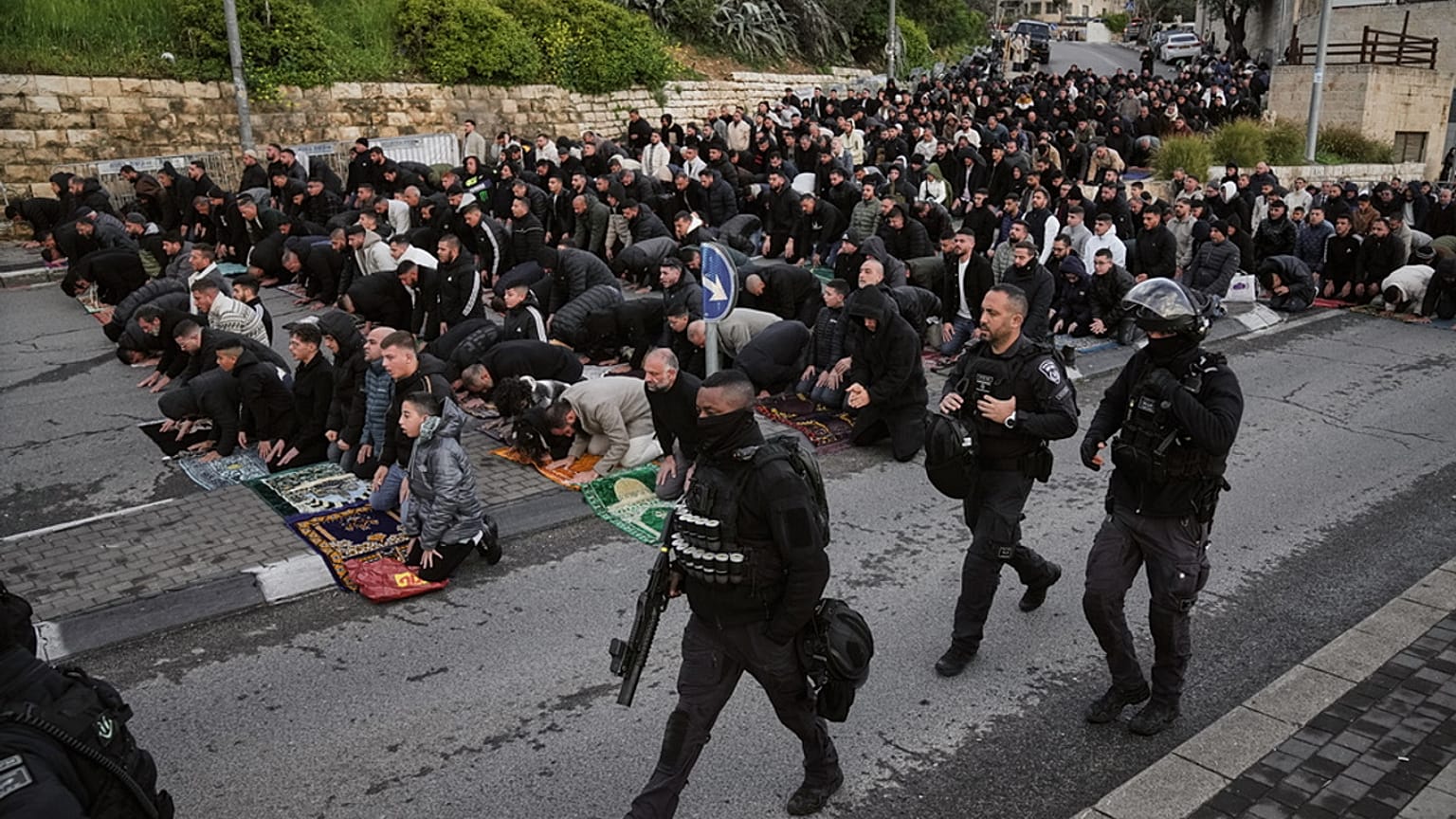 عناصر من الشرطة الإسرائيلية يمرّون قرب مصلّين فلسطينيين يؤدّون صلاة عيد الفطر بالقدس، في 20 مارس 2026.