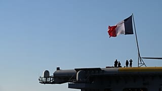 Des officiers de la Marine nationale française se tiennent à bord du porte-avions Charles de Gaulle, au large de la banlieue de Faliro, à Athènes, le jeudi 24 mars 2022.