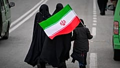 امرأتان وطفل يحملان العلم الإيراني يسيرون باتجاه جامع الإمام الخميني الكبير لحضور صلاة الجمعة في طهران