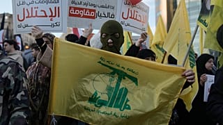 أحد أنصار حزب الله يحمل علم الجماعة خلال احتجاج يدين الأعمال العسكرية الإسرائيلية الأخيرة في لبنان 