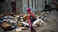 Una donna passa accanto a cumuli di rifiuti in una strada dell'Avana, Cuba, giovedì 19 marzo 2026. (Foto AP/Ramon Espinosa)