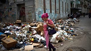 A woman walks past piles of rubbish on a street in Havana, Cuba, on Thursday, 19 March 2026. (AP Photo/Ramon Espinosa)