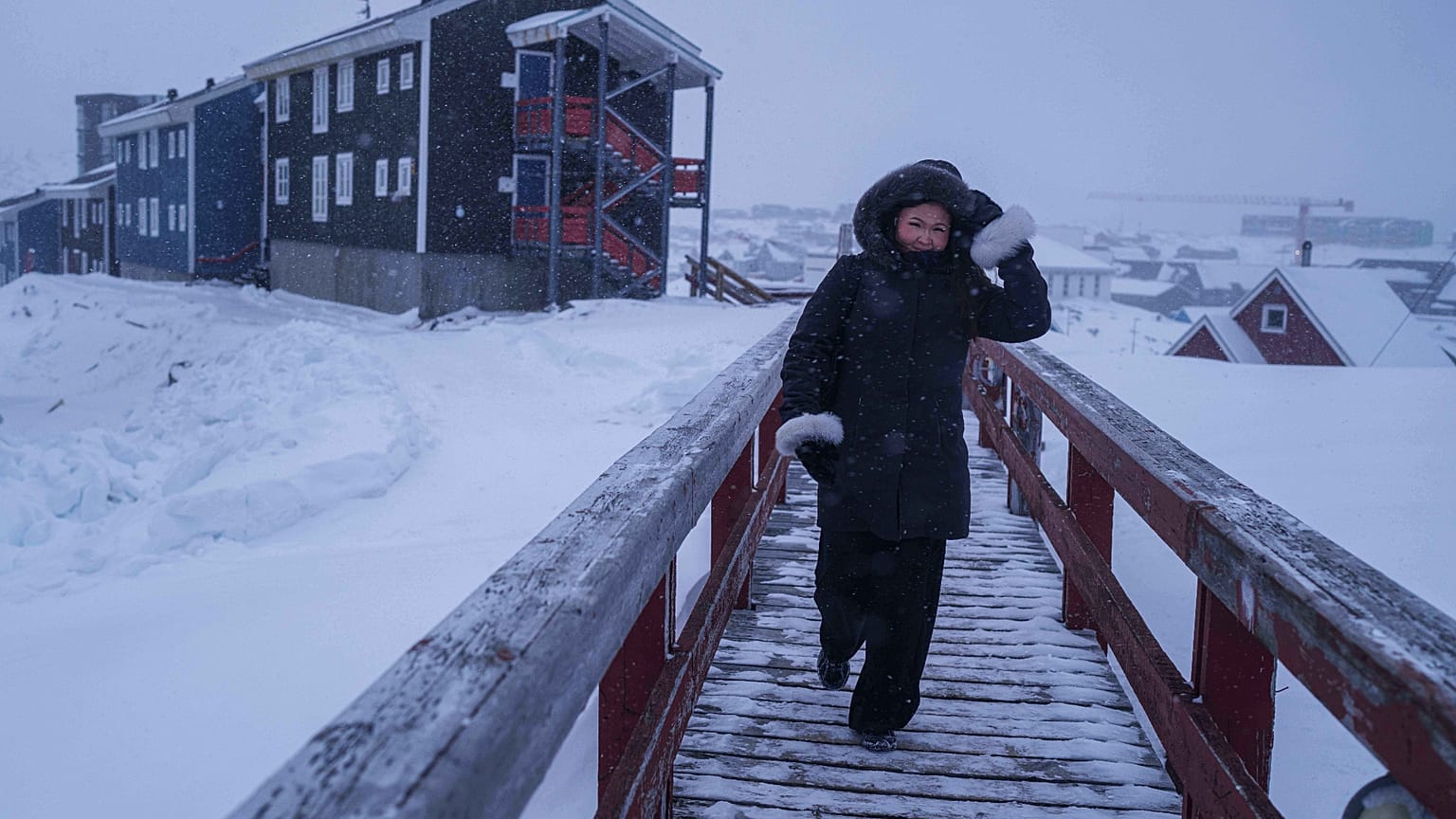 أحد المشاة يعبر الجسر بينما تتساقط الثلوج في نوك، جرينلاند، الاثنين 19 يناير 2026.
