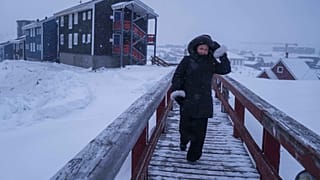 أحد المشاة يعبر الجسر بينما تتساقط الثلوج في نوك، جرينلاند، الاثنين 19 يناير 2026.