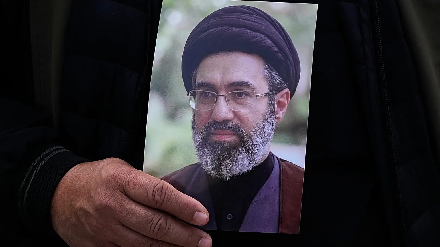 رجل يحمل صورة مجتبى خامنئي خلال تشييع الجنرال علي محمد نائيني في طهران، 21 مارس/آذار 2026.