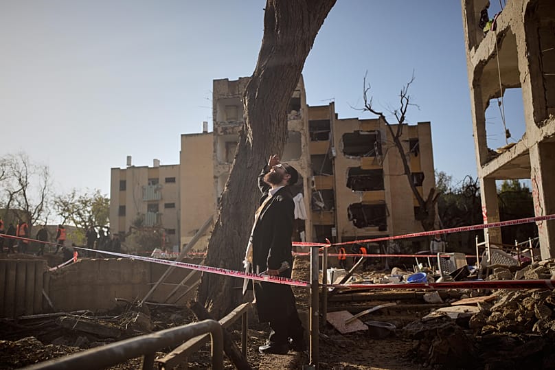 A man looks at residential buildings damaged by an Iranian missile strike in Arad, southern Israel, Sunday, March 22, 2026. 
