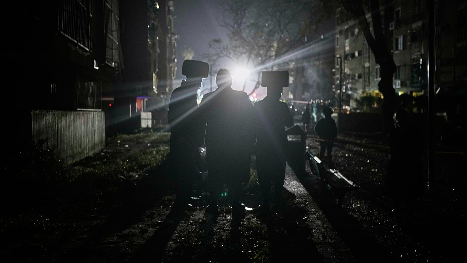 رجال يهود أرثوذكس متطرفون يشاهدون قوات الأمن الإسرائيلية وفرق الإنقاذ تعمل في الموقع الذي أصيب بصاروخ إيراني