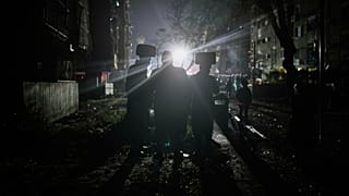 رجال يهود أرثوذكس متطرفون يشاهدون قوات الأمن الإسرائيلية وفرق الإنقاذ تعمل في الموقع الذي أصيب بصاروخ إيراني