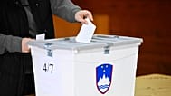 Une électrice dépose son bulletin dans un bureau de vote lors des élections législatives à Arnace, en Slovénie, le dimanche 22 mars 2026.