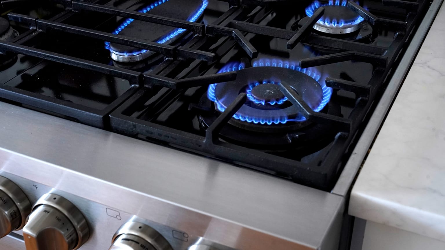 Flames emerge from burners on a natural gas stove.