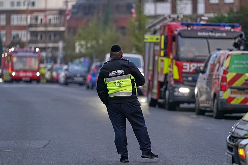 An officer from an emergency response unit watches a firefighter response team in London, Monday, March 23, 2026 after an apparent arson attack four Jewish ambulance vehicles.