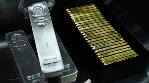 FILE - An employee of Pro Aurum gold house lifts 1 Kg silver bars of 999.9 purity besides 1 Kg gold bars in the safe deposit boxes room in Munich, Germany. 25 April 2025.