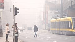 Ein Mann mit Atemschutzmaske überquert eine Straße im Smog von Sarajevo in Bosnien am Mittwoch, 22. Januar 2025.