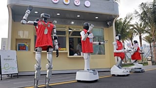 Robot volunteers standing in front of the robot volunteer service station at the Qianhaishi Park, China. 