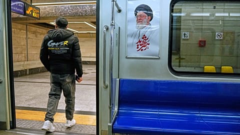 FILE: A man leaves a subway train past an image of the late Iranian Ayatollah Ali Khamenei, in Tehran, 13 March 2026