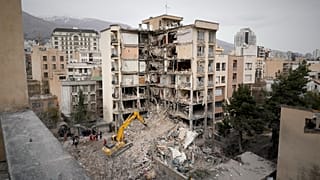 A Vörös Félhold munkásai takarítják el egy csapásokban megrongálódott ház romjait Teheránban 