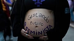 Una donna partecipa a una marcia femminista con la pancia dipinta con un messaggio.