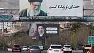 تسير المركبات تحت لوحات إعلانية تظهر صور المرشد الأعلى الإيراني الراحل آية الله علي خامنئي، في المقدمة، وابنه آية الله مجتبى خامنئي، خليفته