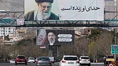 تسير المركبات تحت لوحات إعلانية تظهر صور المرشد الأعلى الإيراني الراحل آية الله علي خامنئي، في المقدمة، وابنه آية الله مجتبى خامنئي، خليفته