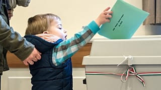 Egy választópolgár a gyermeke segítségével adja le szavazatát a csíkszeredai magyar főkonzulátuson az országgyűlési képviselő-választáson 2018. április 8-án.