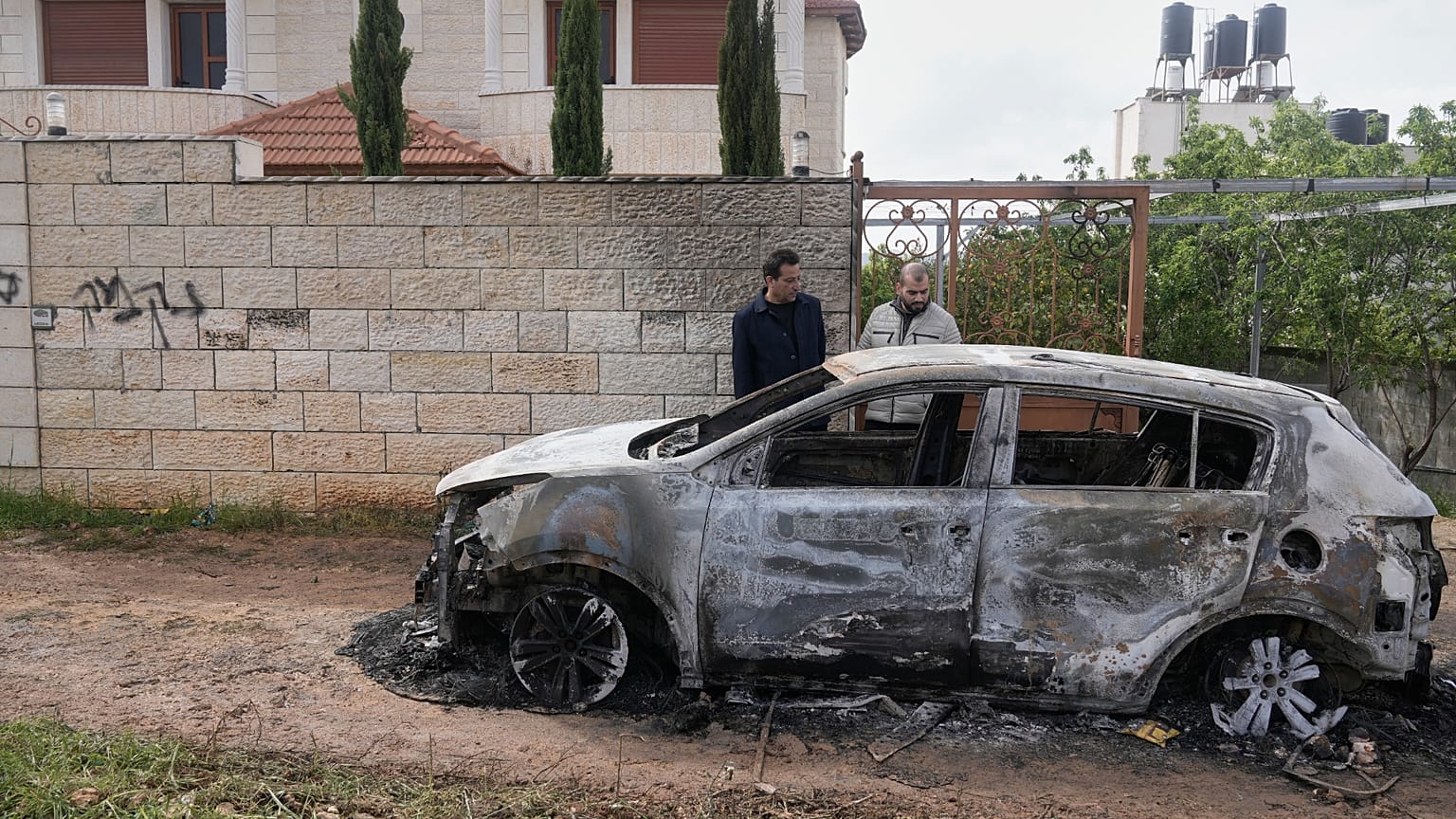 فلسطيني يتفقد سيارته المدمرة في هجوم شنه مستوطنون، 21 نوفمبر/تشرين الثاني 2025.