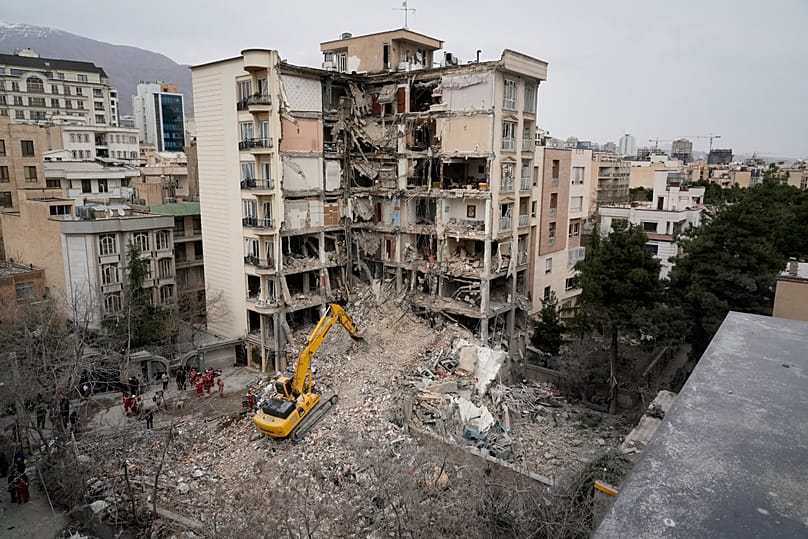 Iranian Red Crescent emergency workers use a bulldozer to clear rubble from a residential building that was hit in Tehran, 23 March, 2026