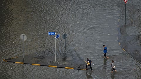 Los viajeros avanzan a pie por una calle inundada tras fuertes lluvias en Sharjah, Emiratos Árabes Unidos, el miércoles 25 de marzo de 2026.