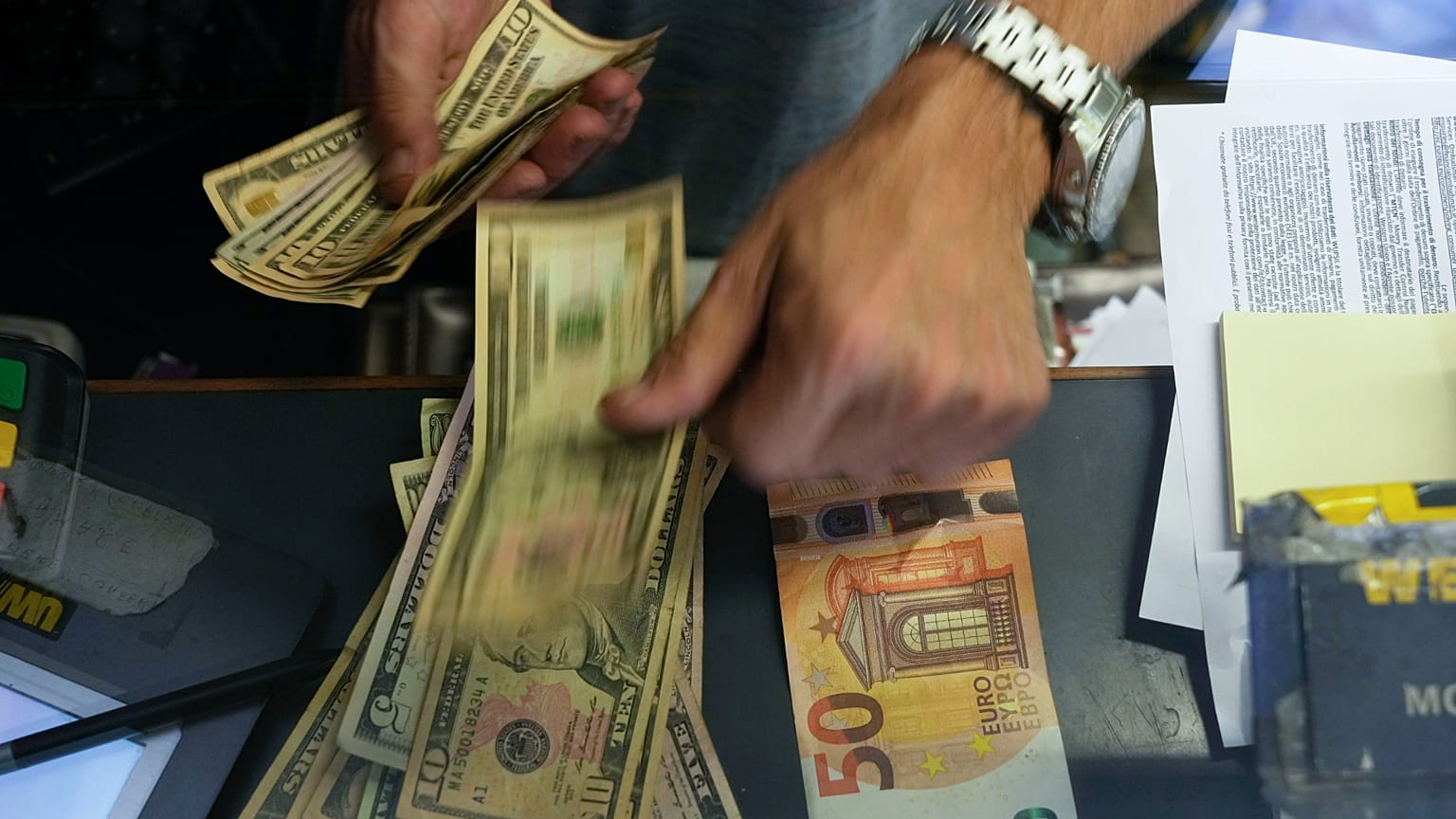A cashier changes a 50 Euro banknote with US dollars at an exchange counter in Rome, Wednesday, July 13, 2022.