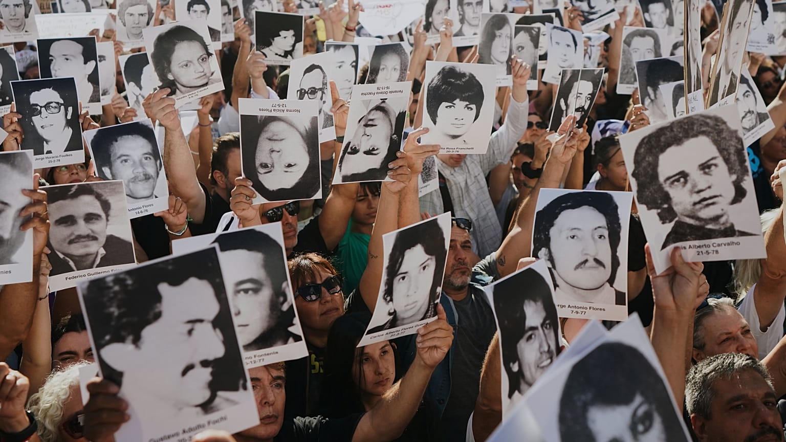 Manifestantes exhiben fotografías de personas desaparecidas durante la dictadura militar argentina (1976-1983) en una concentración por el aniversario del golpe de Estado.