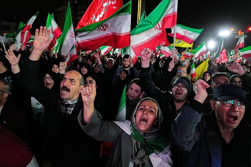 Pro-government supporters chant slogans and wave Iranian flags during a rally, in a square in western Tehran, Iran, Wednesday, March 25, 2026